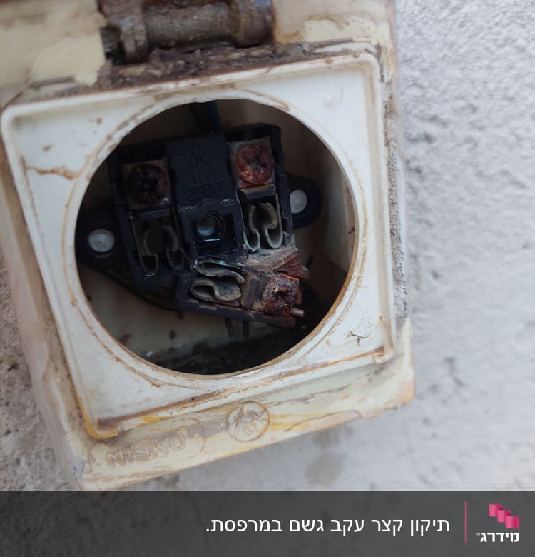 שקע חשמלי פתוח עם חלודה וחוטים חשופים